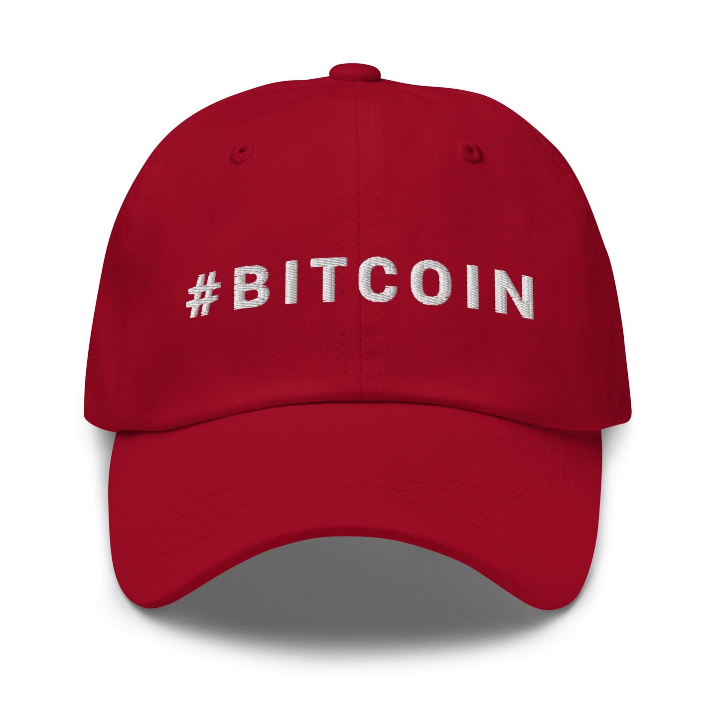 Introducing the Hashtag Hat, a stylish red baseball cap embroidered with "#BITCOIN" in bold white capital letters on the front. Designed with a curved brim and distinct stitching along its seams, this cap adds a trendy touch reminiscent of fashionable cities like Sydney while boasting a three-dimensional appearance enhanced by its shadowing.