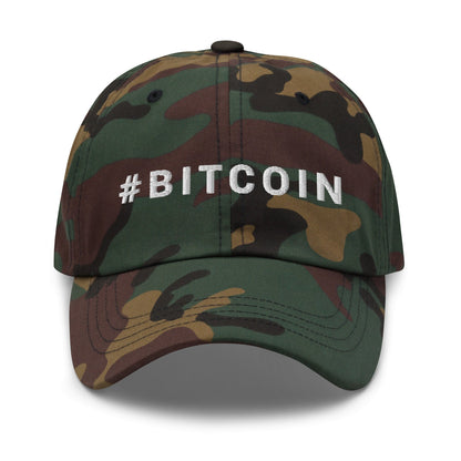 Introducing the Hashtag Hat: a rugged baseball cap featuring a camouflage design with a blend of green, brown, and black tones that embodies the adventurous spirit of Australia. "#BITCOIN" is meticulously embroidered in white capital letters on the front. Ideal for sunny days in Sydney or adventures in Queensland, this cap sports a curved brim and a shadow-casting button on top.