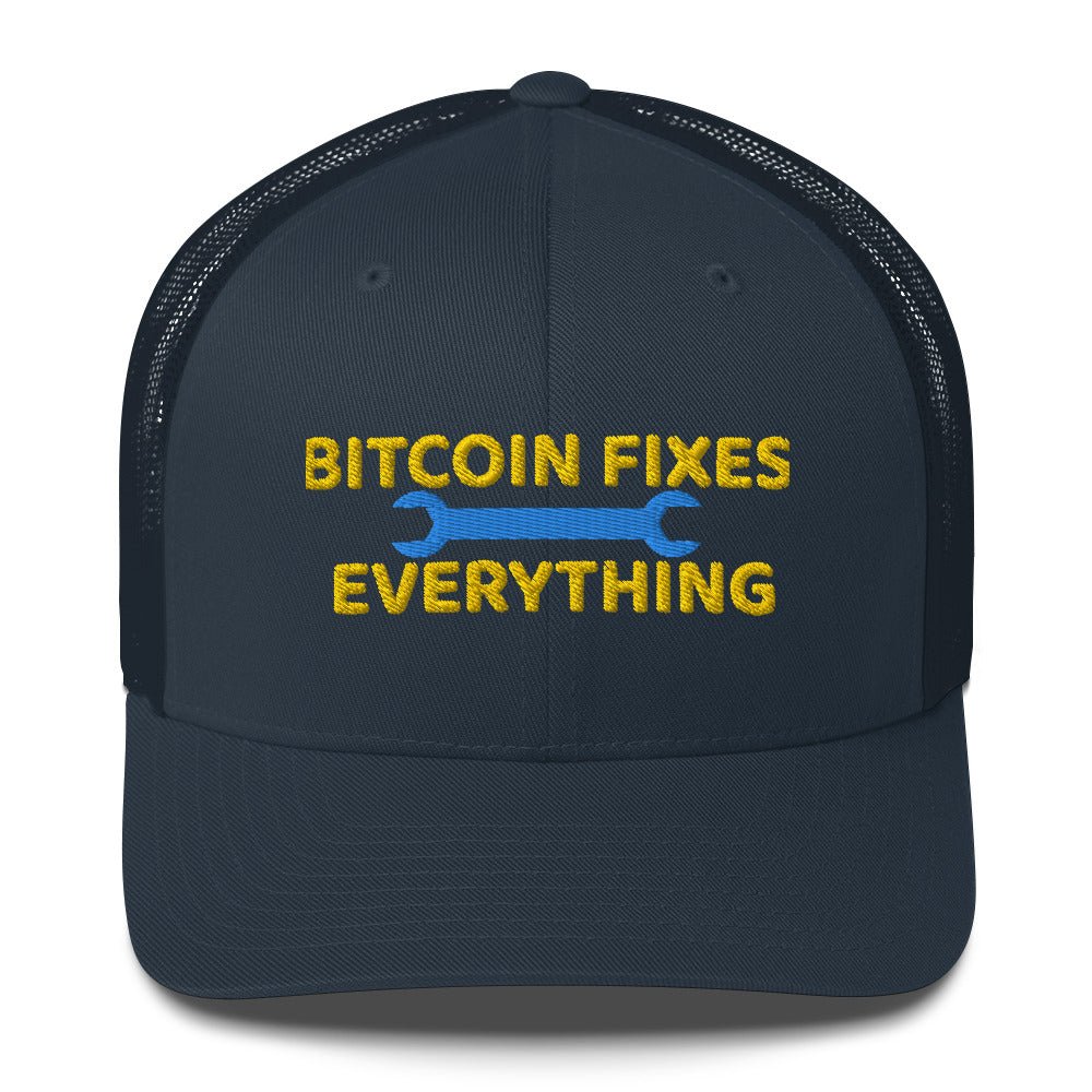 A dark UTXO Dreams trucker hat with a mesh back featuring an embroidered slogan in yellow "Bitcoin Fixes Everything" with two blue wrenches on either side of the text.